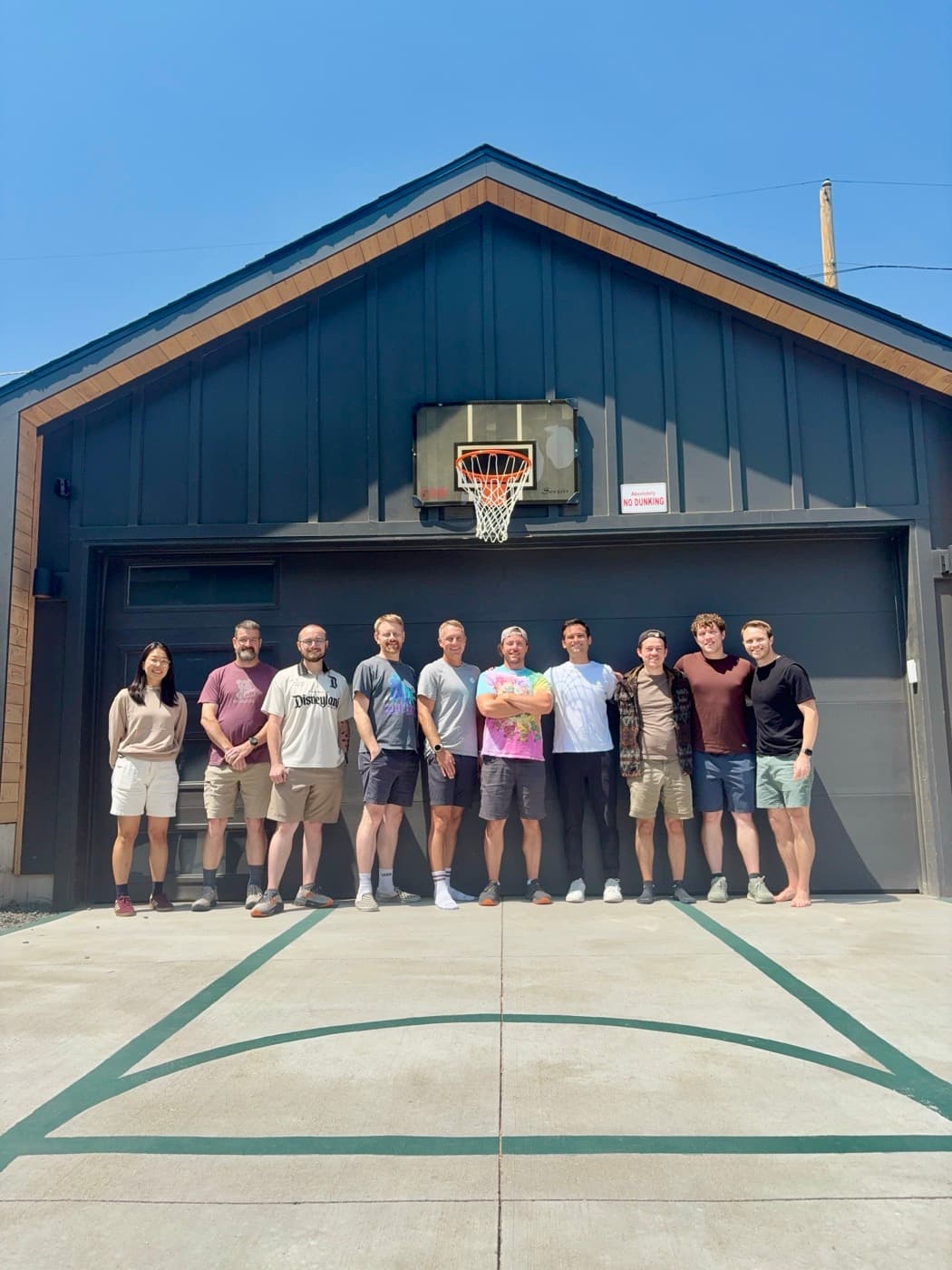 Teammates posing together in front of a garage basketball hoop